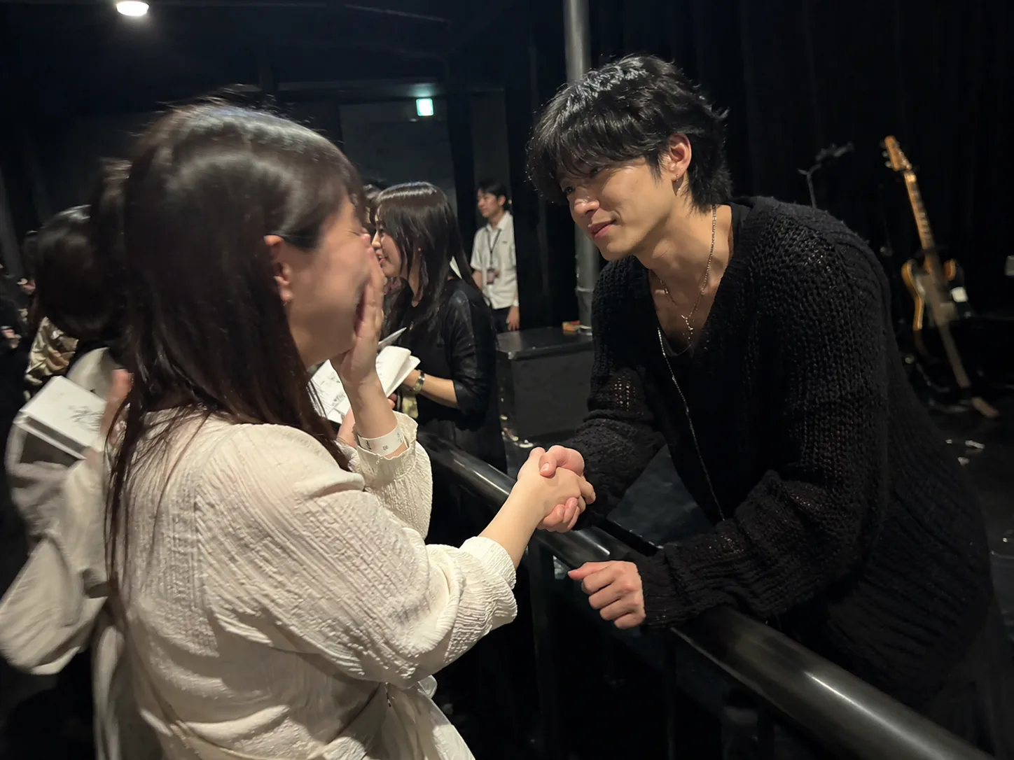 ライブ終演後、ファンとアーティストが笑顔で握手を交わしている