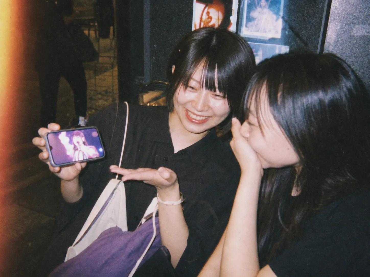 ライブハウスの前で、購入したクリップを友人に見せて自慢するファン